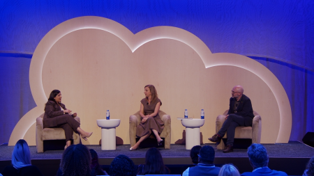 A three shot of two women and one man seated on stage