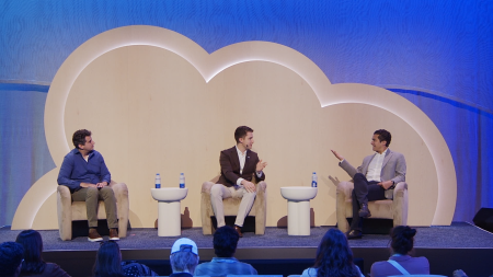 There are three people on stage sitting in chairs and having a conversation
