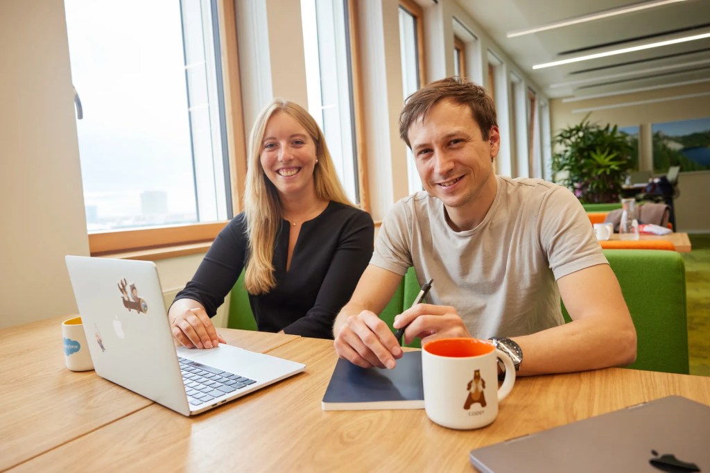 モダンなオフィスで同じテーブルに座って共同作業している男性と女性。